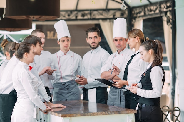 Restaurantmanager en zijn personeel op het terras, interactie met chef-kok in restaurant,