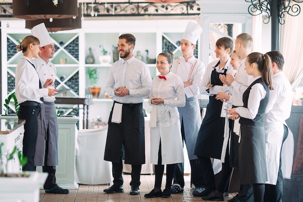 Restaurantmanager en zijn personeel op terras. interactie met chef-kok in restaurant.