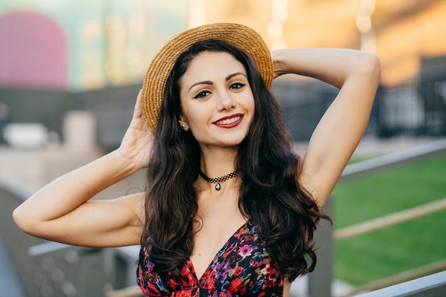 Restful brunette lady with beautiful make-up wearing summer hat and dress