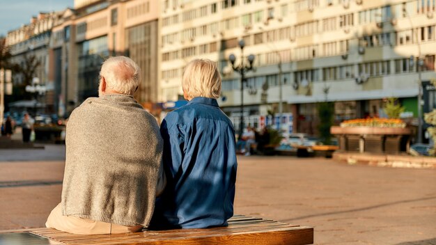 Resting back view of senior couple in casual clothes sitting on the bench together