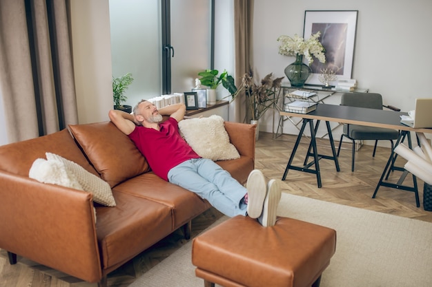 Resting. Grey-haired man sitting on the sofa and resting