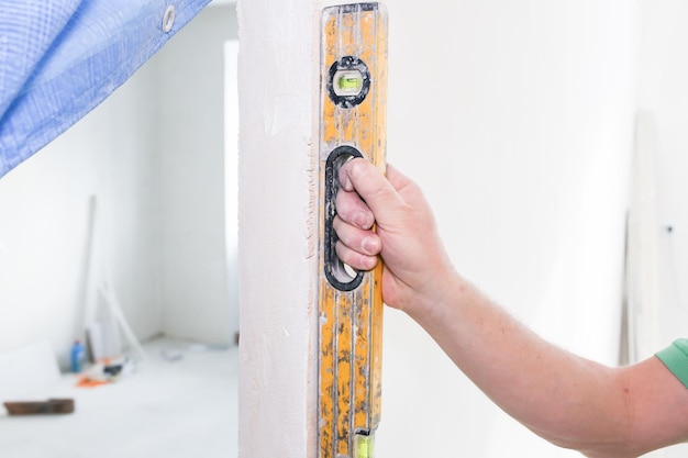 Restoration with bubble level indoors Man is holding a spirit level in hands Maintenance repair works renovation in the flat