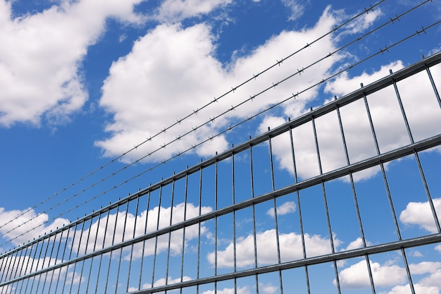 Concetto di area riservata. recinzione metallica con filo spinato su uno sfondo di cielo blu. rendering 3d