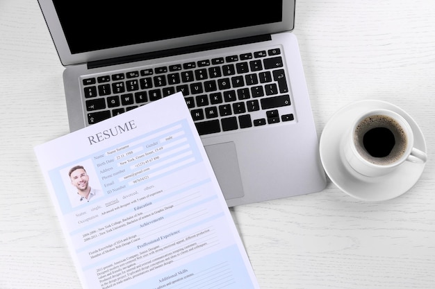 Resume and laptop on wooden table