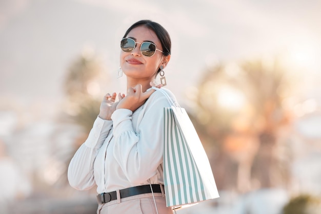 Retail shopping bag urban woman and portrait travel for discount sales market and outdoor sun in Dubai Happy rich arab customer consumer and wealthy person with sunglasses buying luxury fashion