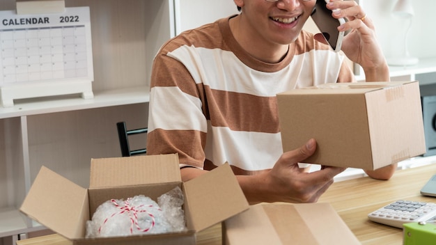 a retailer holding a parcel post while talking with his customer on the mobile phone