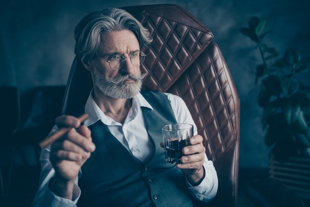 Retired  businessman smoke cigar drink whiskey in loft grey office