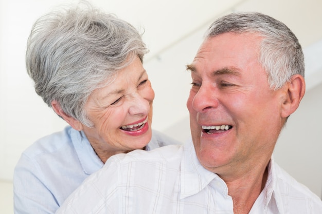 Retired couple smiling at each other and hugging