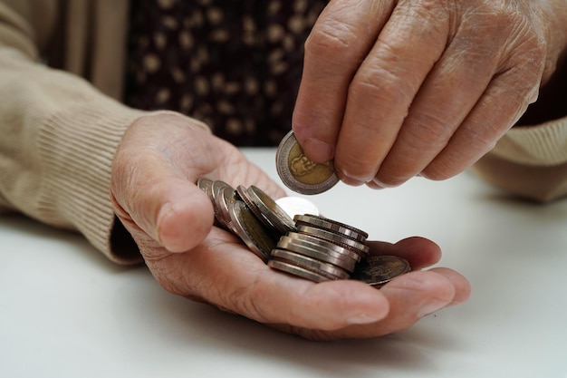 Retired elderly woman counting coins money and worry about monthly expenses and treatment fee payment