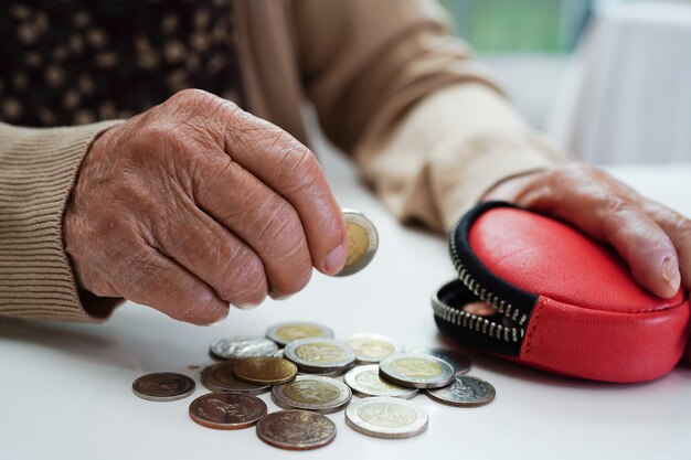 Foto donna anziana in pensione che conta monete denaro e si preoccupa delle spese mensili e del pagamento della quota di trattamento