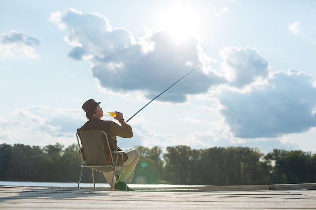 写真 夏にビールを飲み、釣りをする引退した男