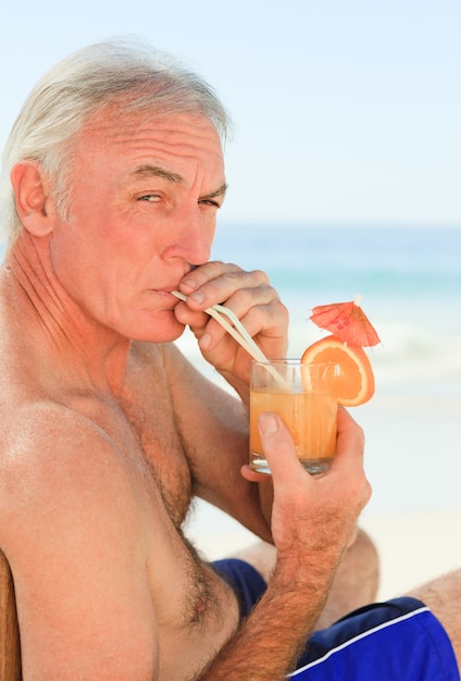 Retired man drinking a cocktail at the beach