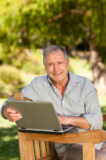 Retired man working on his laptop in the park