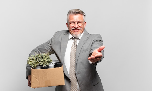 Retired senior businessman smiling happily with friendly, confident, positive look, offering and showing an object or concept