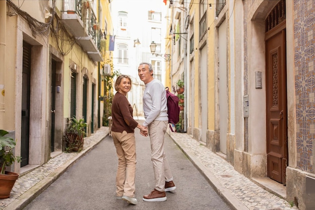 Retired Senior Spouses Walking Carrying Backpack Enjoying Vacation In Europe