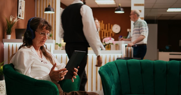 Photo retired traveller using tablet in lobby