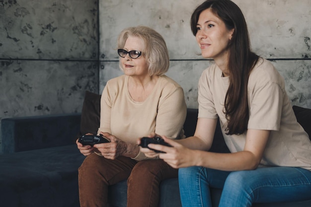 自宅の居間のソファでオンラインで一緒に遊びや対戦ゲームを楽しむ退職した女性 家族 家庭 余暇 活動関係 幸せなライフスタイル