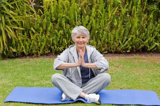 Photo retired woman practicing yoga in the garden