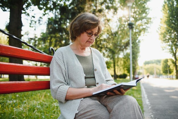 Retired woman reading a book on the bench