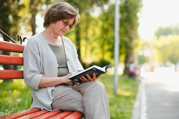 Retired woman reading a book on the bench