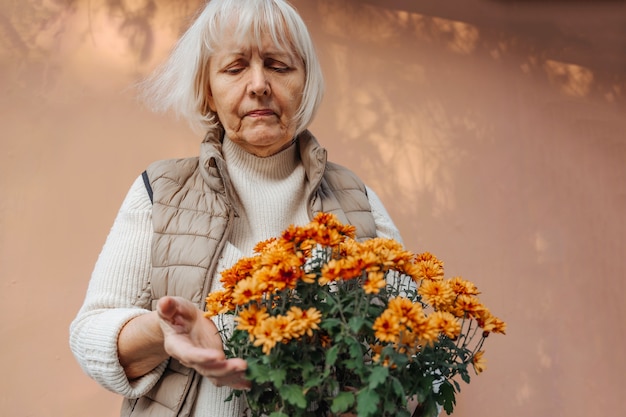 写真 鉢植えの装飾花の世話をしている引退した女性。