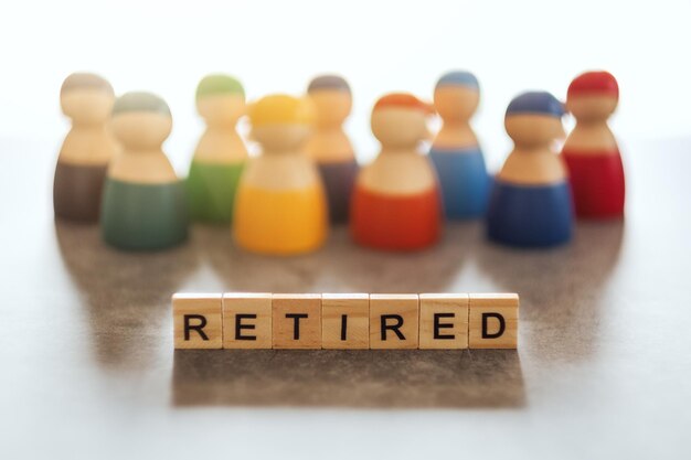 Photo retired word on wooden blocks with a group of elder people in the background