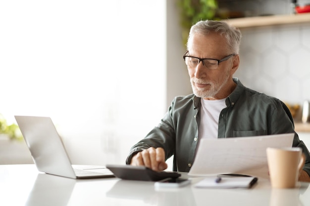 Retirement and finances smiling senior gentleman calculating taxes at home