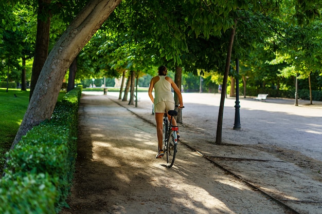 自転車でスポーツをしている人々と日の出の夏の日にマドリードのレティーロ公園。