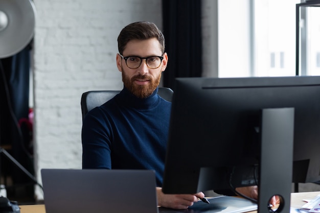 Photo retouching images in special program.portrait of graphic designer working in office with laptop,monitor,graphic drawing tablet and color palette.retoucher workplace in photo studio.creative agency.