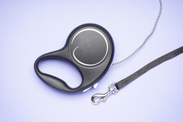 Retractable dog leash on a purple background, flat lay.