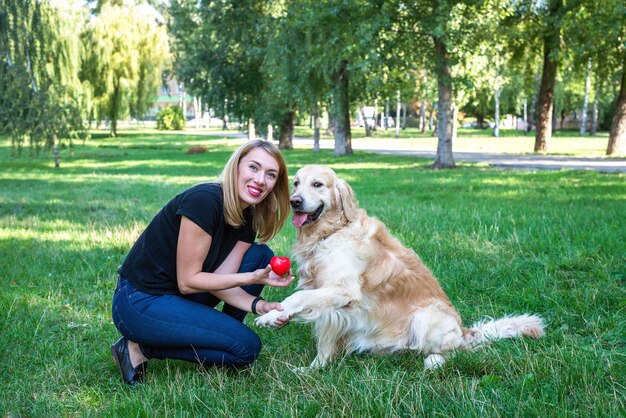 赤いハートを持っているレトリーバー犬と女性。動物を愛するという概念