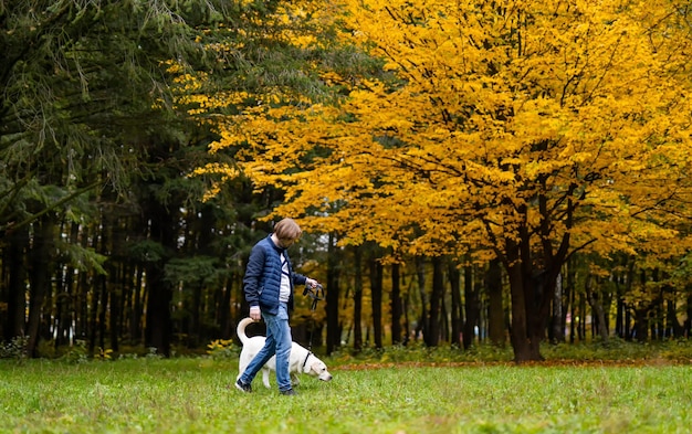 Retriever and and owner man are running in park Golden leaves on trees Fabulous autumn Best friend forever concept