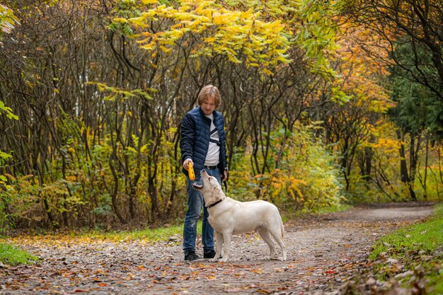 Retriver hond en eigenaar man met een wandeling in een park. Warme herfst in stadspark.
