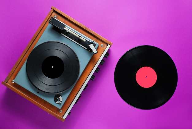 Photo retro 70s vinyl record player with a vinyl record on a purple background