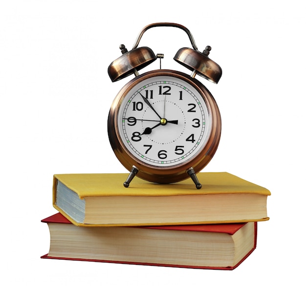 Retro alarm clock and books isolated on white .