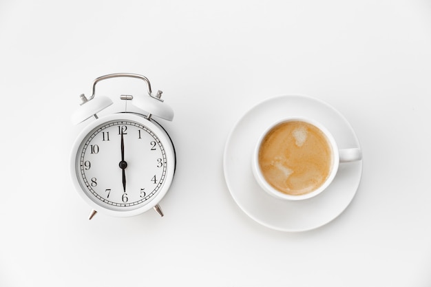 Photo retro alarm clock and a cup of coffee on a white background. concept of early morning ascents. timing. first shift at school or at work.