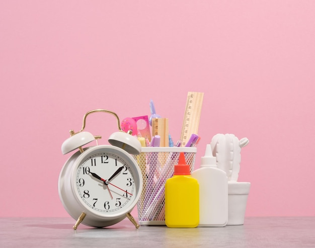 Retro alarm clock office stationery and workplace Glue pens pencils ruler and white cactus statuette