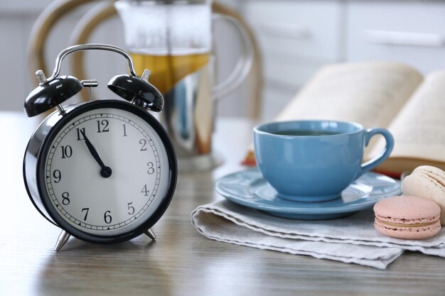 Photo retro alarm clock showing five minutes to eleven on lunch table