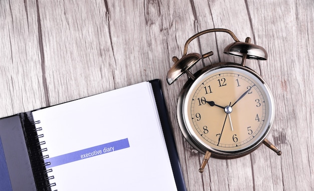 Photo retro alarm clock with notebook paper on table