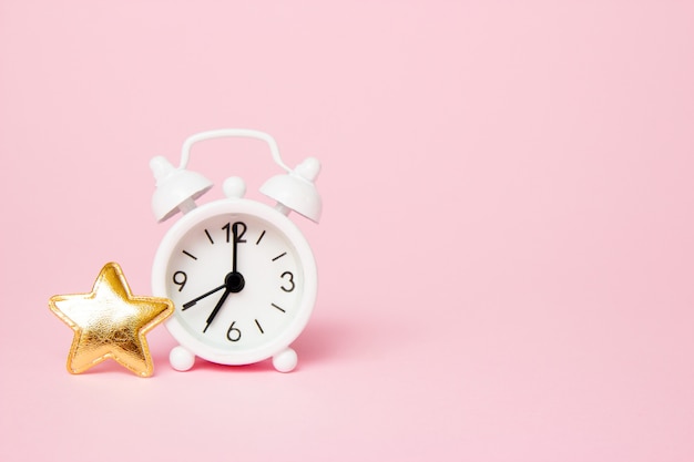 Retro alarm clock with party decoration on pink background
