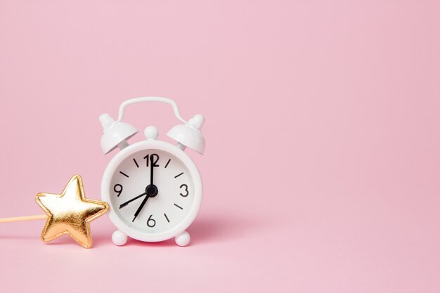 Retro alarm clock with party decoration on pink background