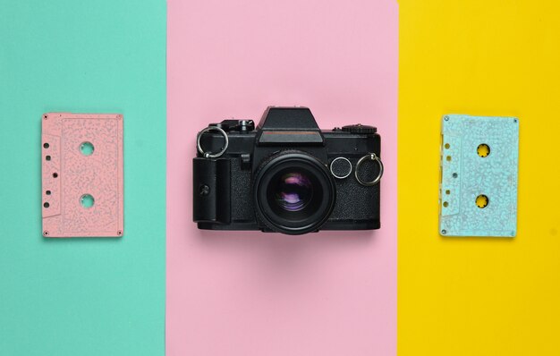 A retro audio cassette tape pastel color and a film camera. Copy space. Minimalist trend.