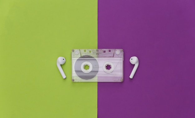 Retro audio cassette and wireless earphones on a purple-green background. 