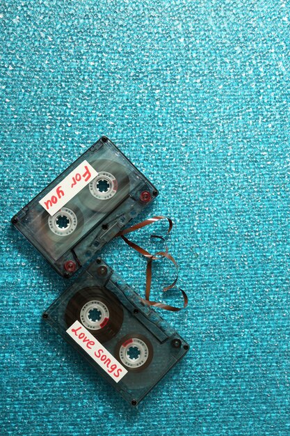 Photo retro audio cassettes with tapes in shape of hearts on blue textured background