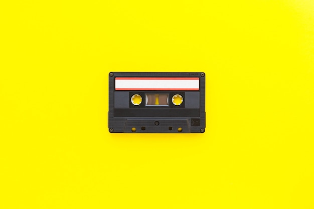 Retro audiobandcassette uit de jaren 80 en 90 geïsoleerd op gele achtergrond. Oud technologieconcept. Plat lag, bovenaanzicht met kopie ruimte.