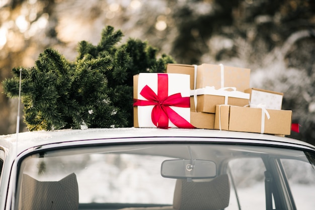 Retro auto met geschenken en een kerstboom in de winter besneeuwde bos. Vakantie decor, Santa Claus levering