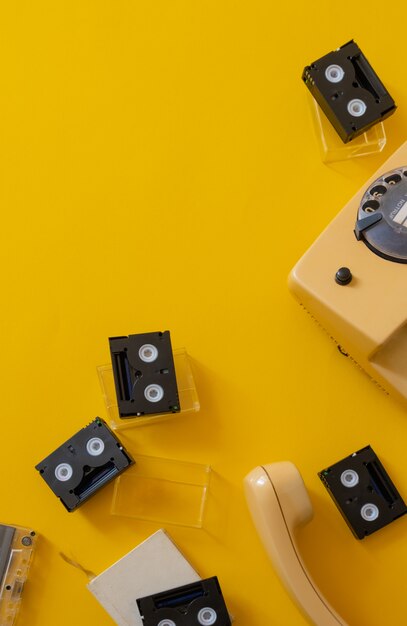 Retro black cassette tape yellow background old phone handset top view copy space