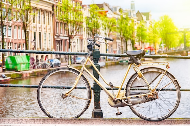 運河に対するオランダ、アムステルダムの橋の上のレトロな自転車
