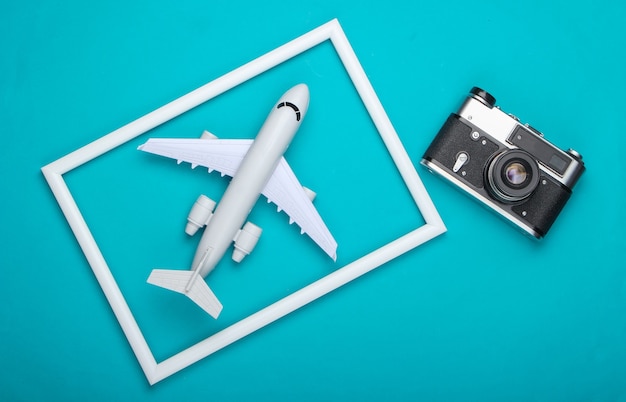 Retro camera and airplane in a white frame on blue surface