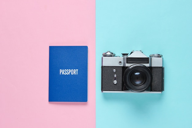 Fotocamera retrò e passaporto su un blu-rosa.